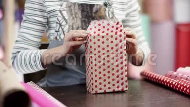 美丽勤劳的女人把蓝色的豪华盒子包装在礼品纸上，作为圣诞礼物或生日礼物送给她